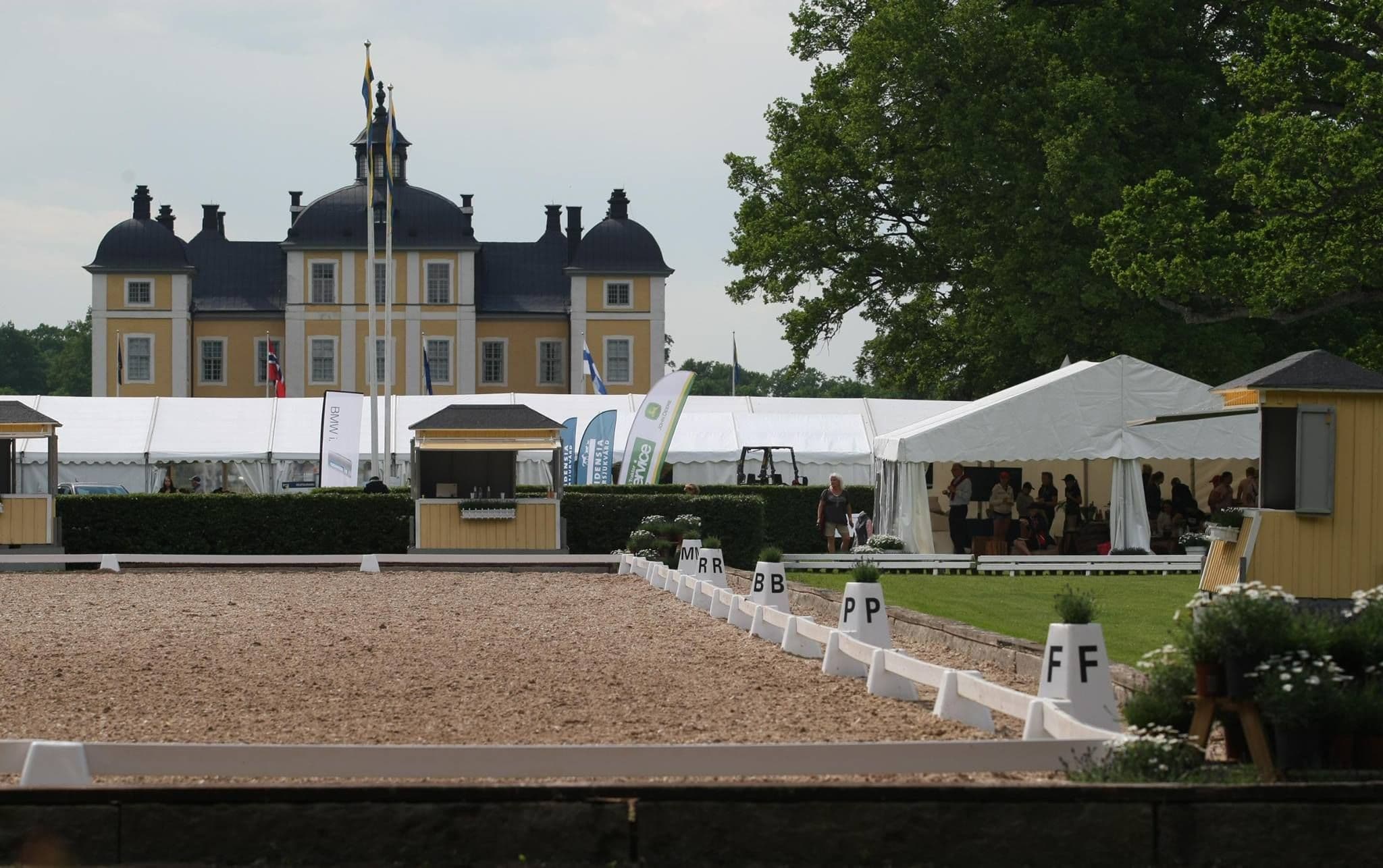 Dressurbane med dressurhegn og bogstavmarkører foran et slot